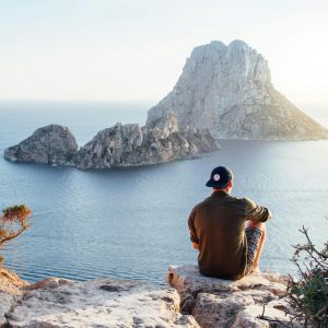Rear View of Man Sitting on Rock by Sea